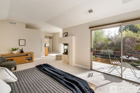 A living room with a grey carpet and a glass door leading to a patio.