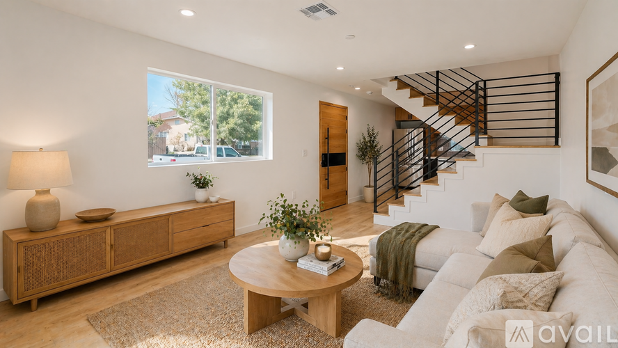 A living room with a white couch, wooden coffee table, and a staircase.