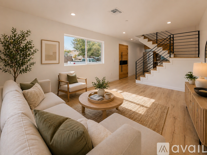 A living room with a white couch, a wooden coffee table, and a staircase.