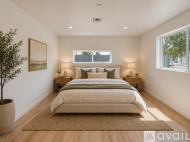 A bedroom with a large bed, a potted plant, and two lamps.