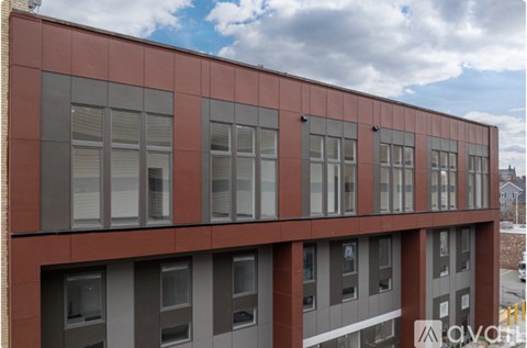 A building with a red and grey facade has a row of windows on the ground floor.