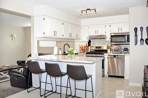 A kitchen with a white counter and bar stools.