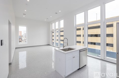 A modern kitchen with white cabinets and a large window.