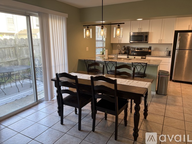 A kitchen with a table and chairs in front of a sliding glass door.