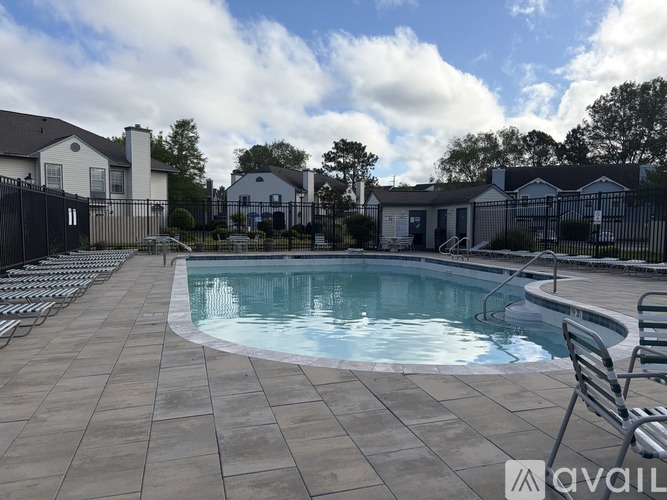 A pool surrounded by a black fence and tiled deck.