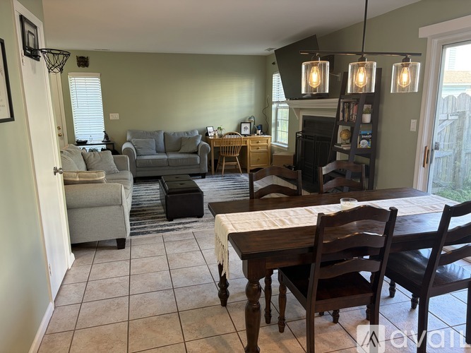 A living room with a grey couch, a wooden table and chairs, and a bookshelf.