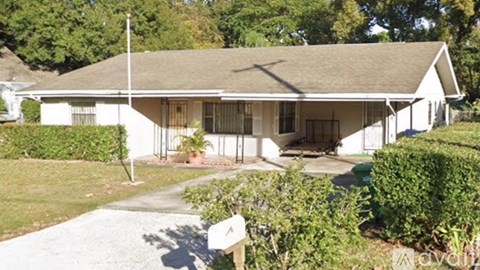 A white house with a brown roof and a grey driveway.
