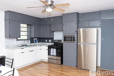 A kitchen with a stainless steel refrigerator and a fan on the ceiling.