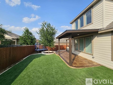 A backyard with a wooden deck and a green lawn.