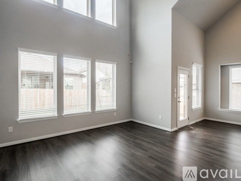 A spacious room with wooden floors and large windows.