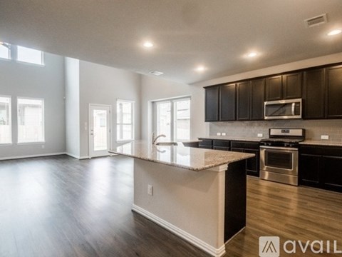 A spacious kitchen with dark brown cabinets and a granite countertop.