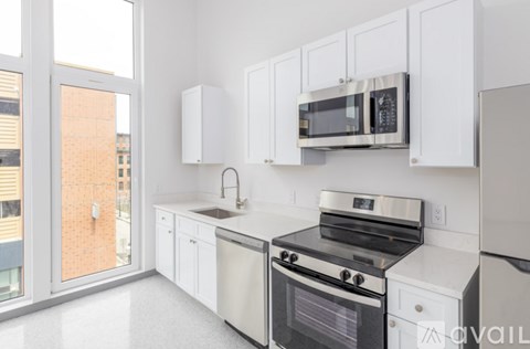 A kitchen with white cabinets and appliances, a sink, and a window.