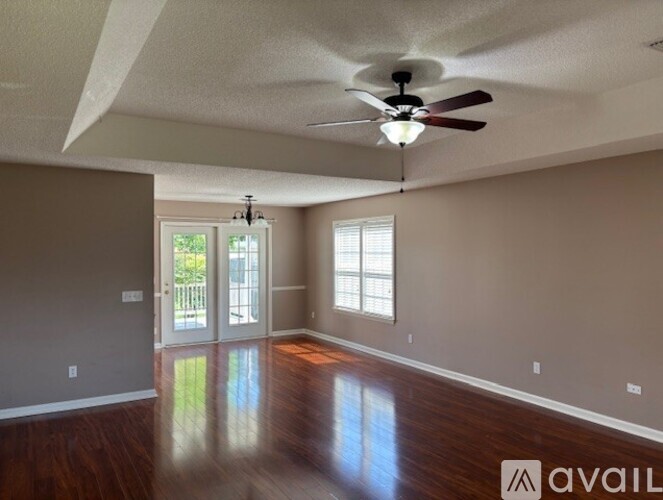 A spacious room with a ceiling fan and sliding glass doors leading to a balcony.