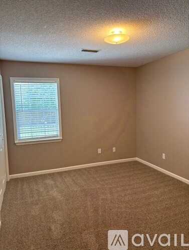 A room with a carpeted floor and a window with blinds.