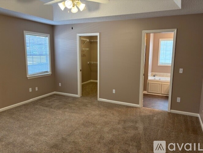 A room with a carpeted floor and a ceiling fan.