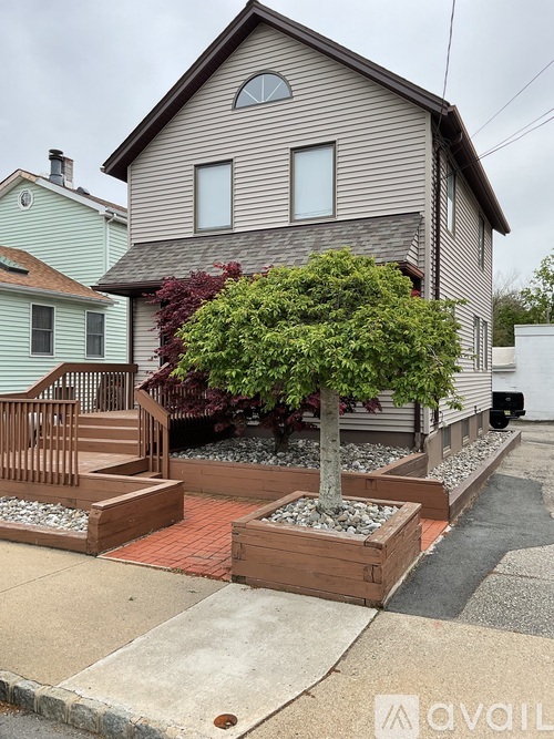 A house with a tree in a planter box in front of it.