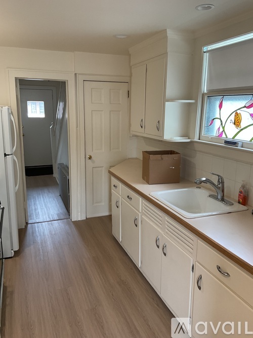 A kitchen with white cabinets and a wooden floor.