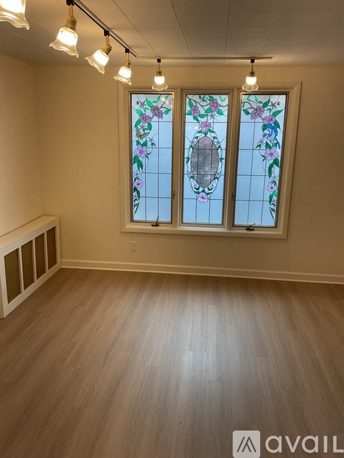 A room with a stained glass window and wooden flooring.