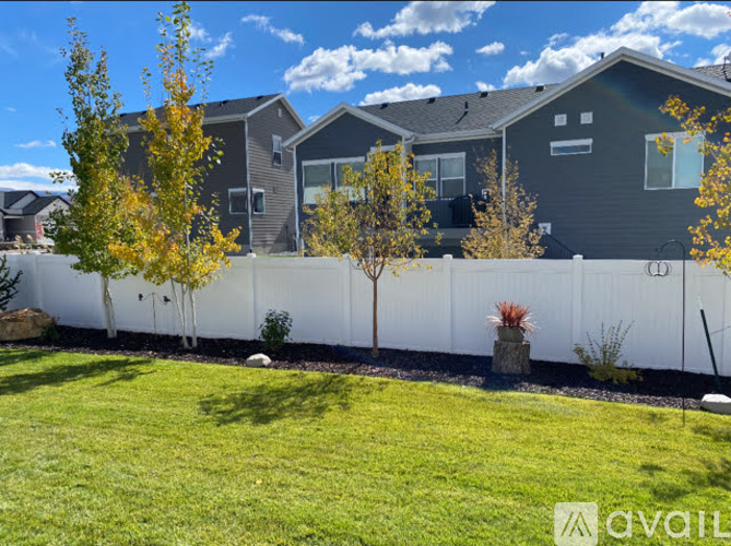 A row of houses with a white fence and green grass in front.