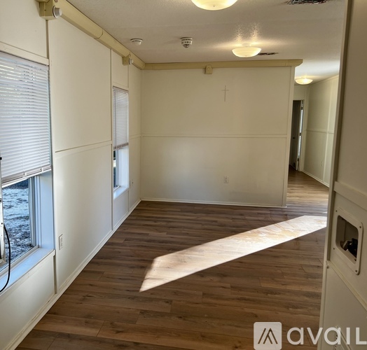 A room with wooden flooring and white walls is available for rent.