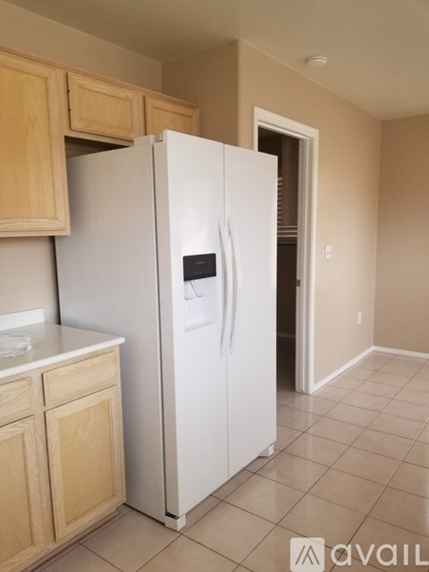 A white refrigerator in a kitchen with wooden cabinets.