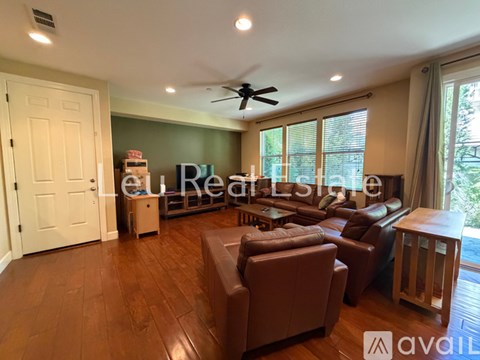 A living room with brown leather furniture and a ceiling fan.
