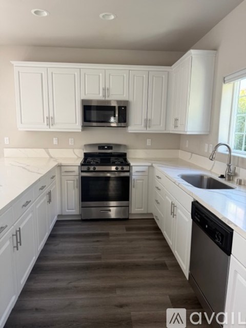A kitchen with white cabinets and a black dishwasher.