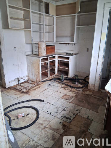A dirty kitchen with a lot of cabinets and a hose on the floor.