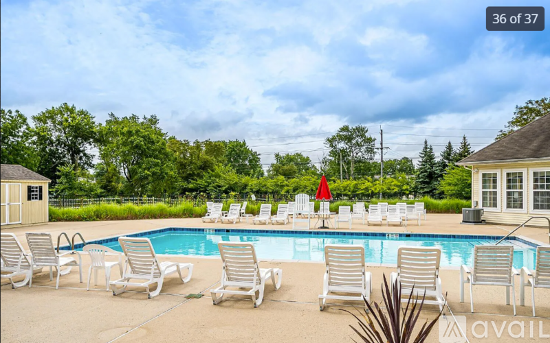 A pool with chairs around it and a red umbrella.