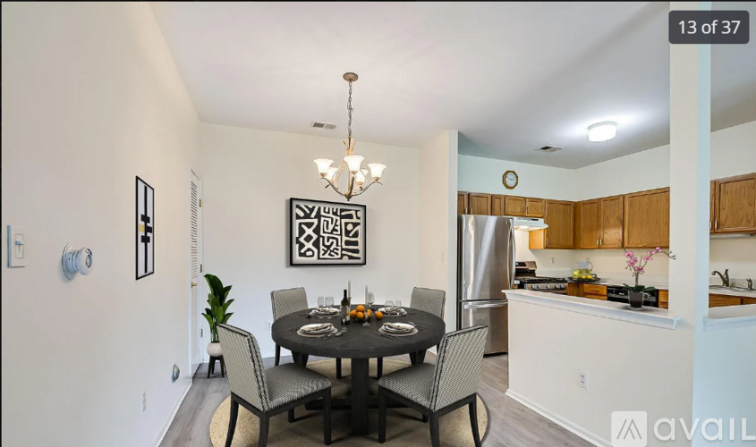 A dining room with a table set for four and a chandelier hanging from the ceiling.