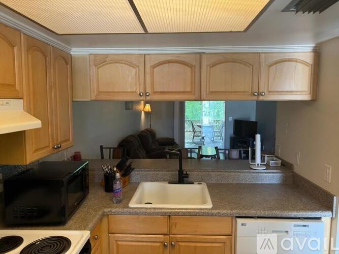 A kitchen with wooden cabinets and a black microwave.