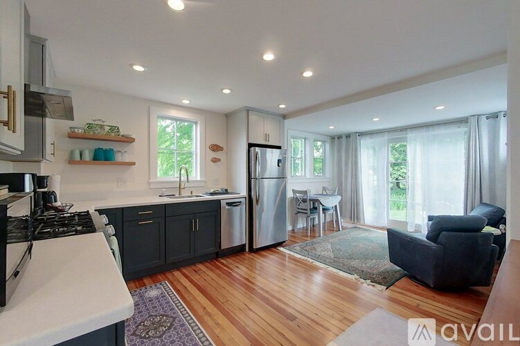 A kitchen with a refrigerator, stove, and a dining table with chairs.