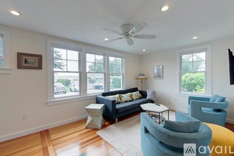 A living room with a blue couch and a ceiling fan.