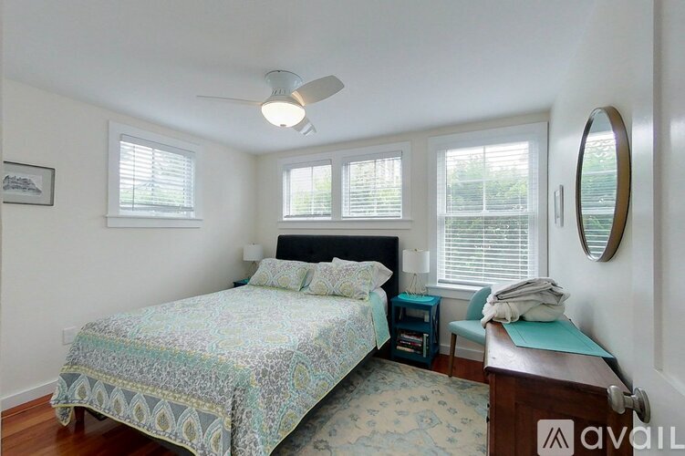 A bedroom with a bed, a chair, and a mirror.