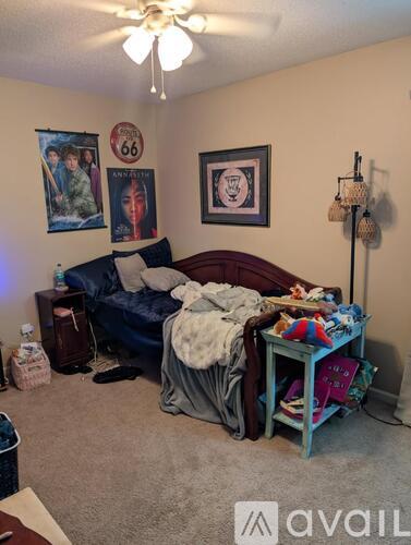 A bedroom with a bed, a couch, a table, and a ceiling fan.