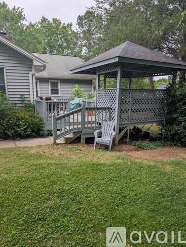 A gazebo is situated in a yard with a house in the background.