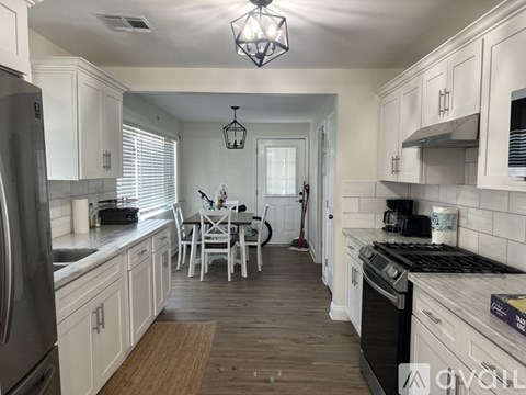 A kitchen with white cabinets and a wooden floor.