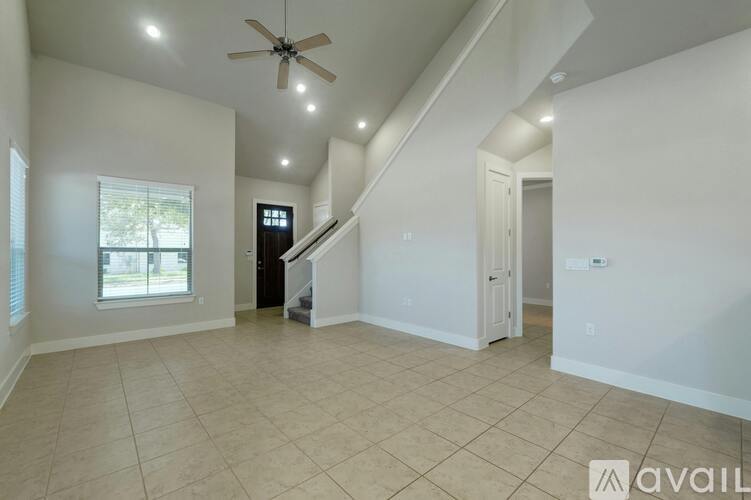 A spacious room with a ceiling fan and a staircase leading to another room.