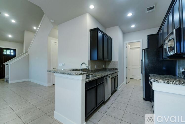 A kitchen with black cabinets and a marble countertop.