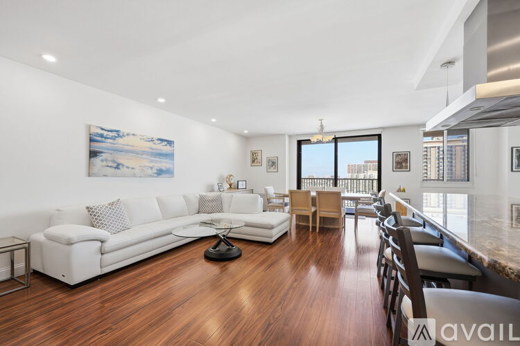 A living room with a white couch and a painting on the wall.