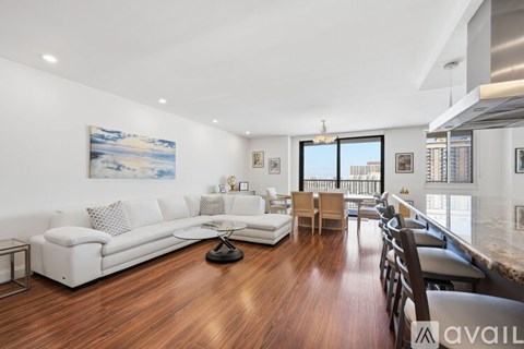 A living room with a white couch and a painting on the wall.