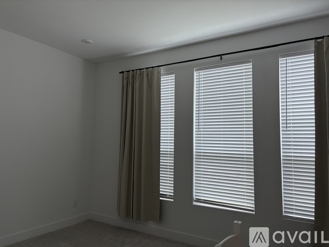 Three windows with white blinds in a room.