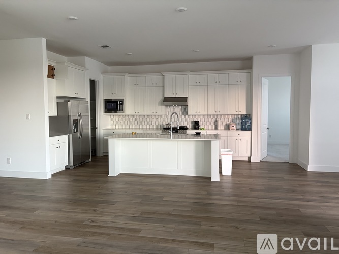 A modern kitchen with white cabinets and a wooden floor.