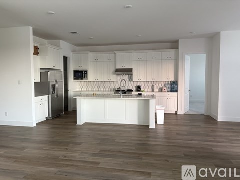 A modern kitchen with white cabinets and a wooden floor.