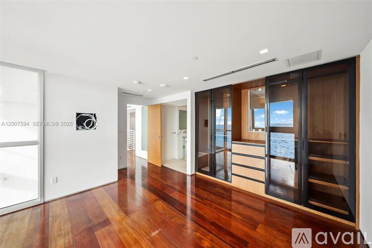 A modern room with wooden floors and a glass door leading to a balcony.