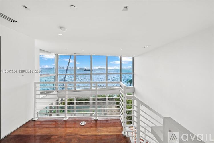 A room with a staircase leading to a balcony with a view of the ocean.