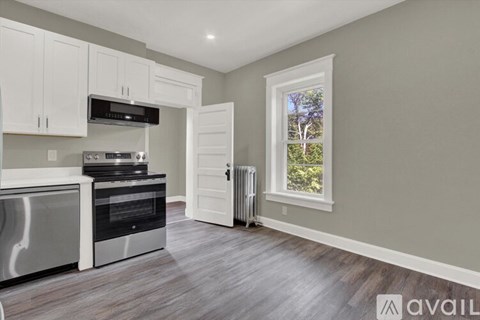 A kitchen with a stainless steel oven and white cabinets.