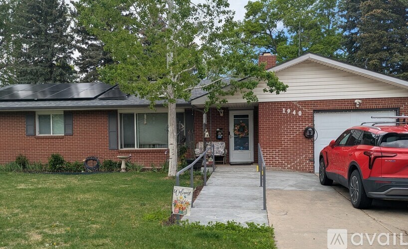 A red brick house with a white garage door and a red car parked in front.