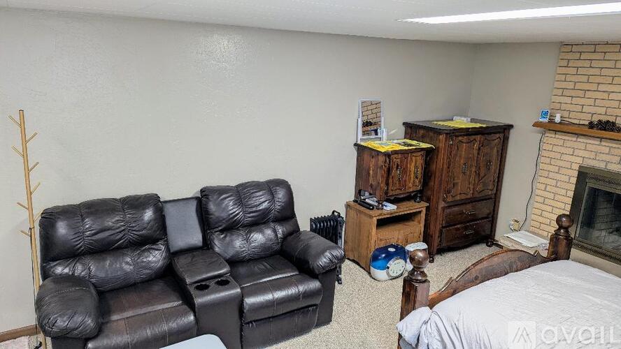 A black leather sofa and chair in a room with a fireplace and a bed.