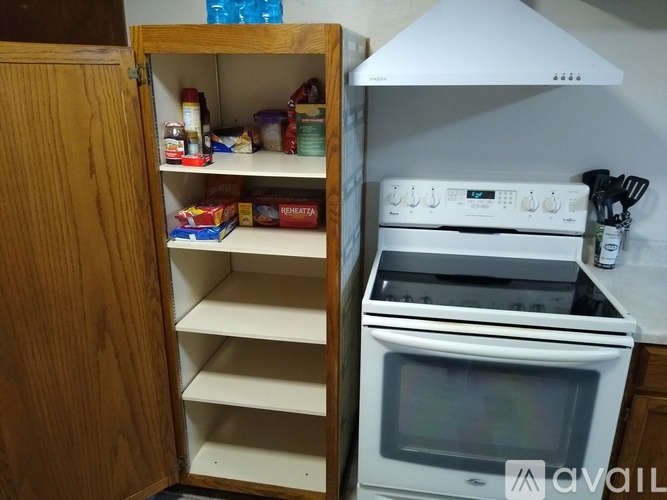 A kitchen with an open cabinet and a white oven.